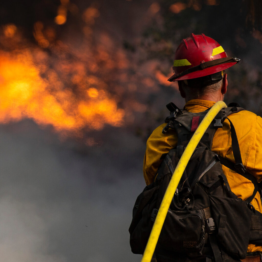 Firefighter stares into background full of fire