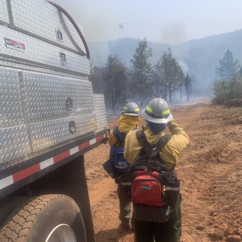 Two firefighters watching helicopter in distance